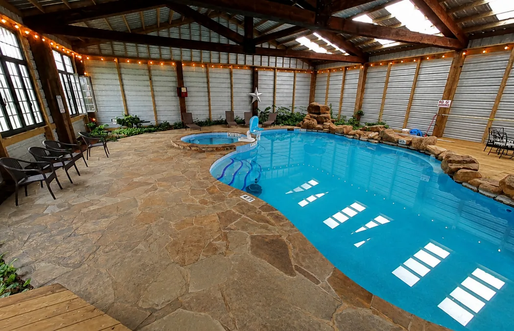 Indoor pool and hot tub with rock walls and string lights